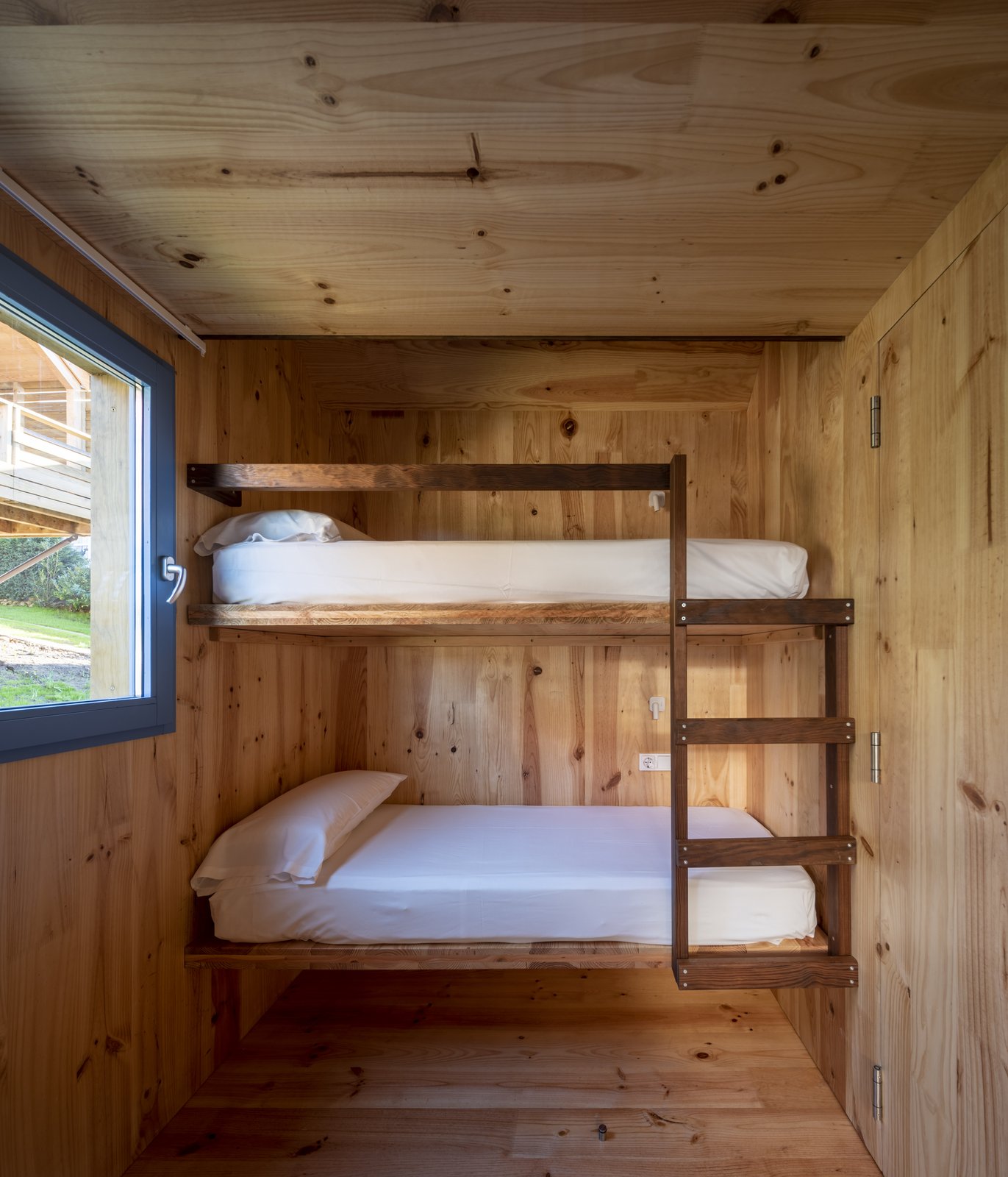 Litera de madera con dos camas individuales en cabaña rústica