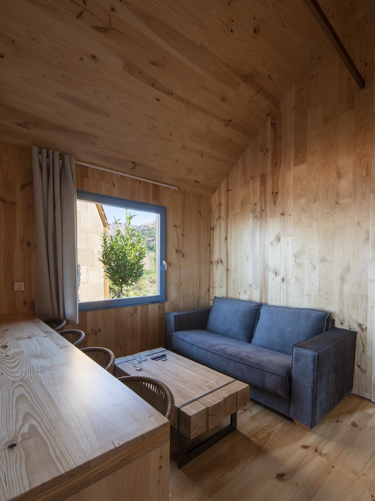Salón de madera con sofá azul, mesa y ventana