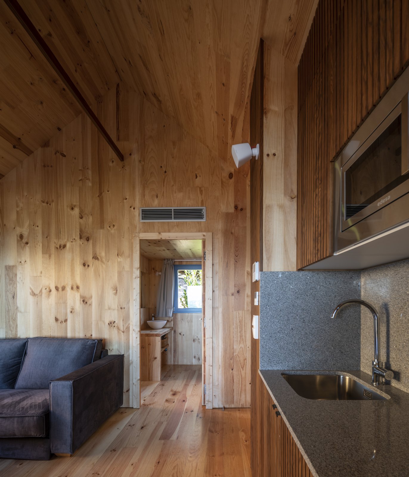 Cabaña de madera con cocina, sofá y baño al fondo