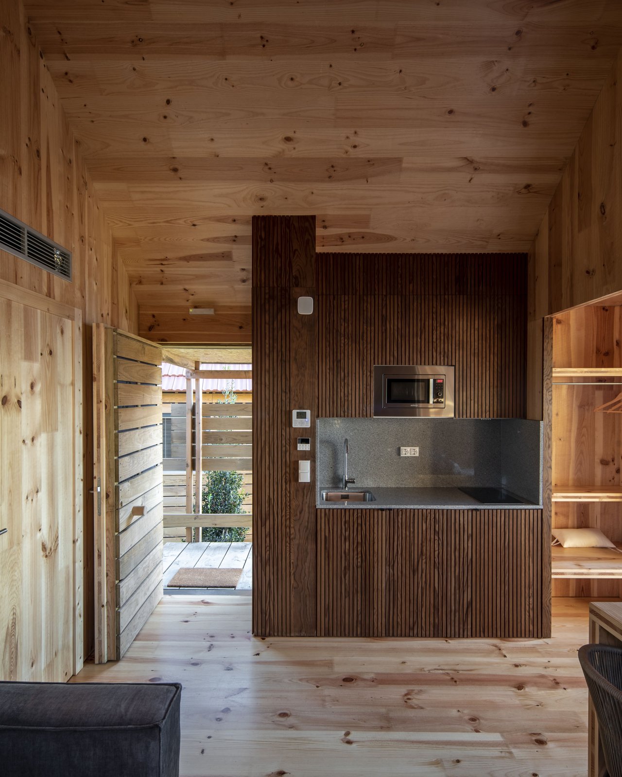 Cocina integrada de madera con microondas empotrado y encimera oscura