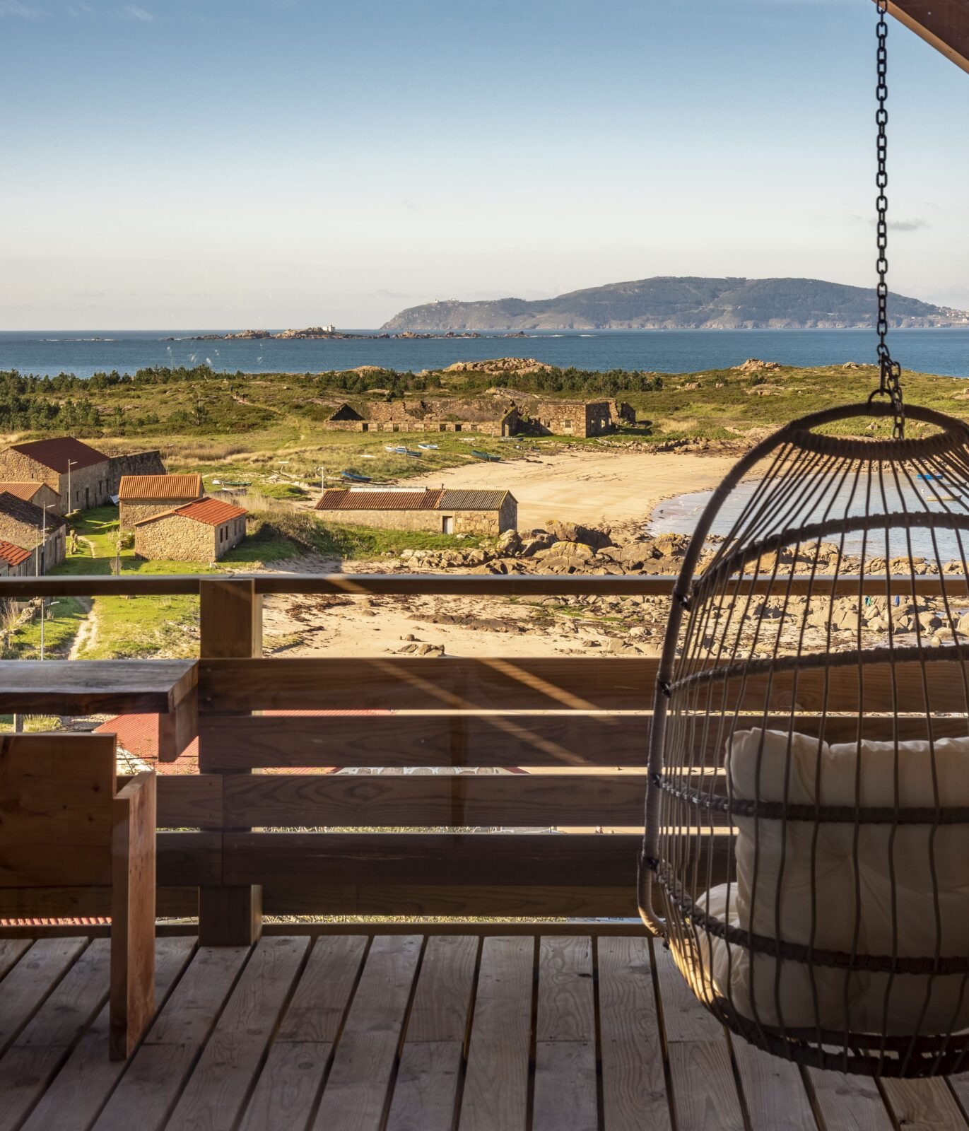 Terraza de madera con silla colgante y vistas al mar